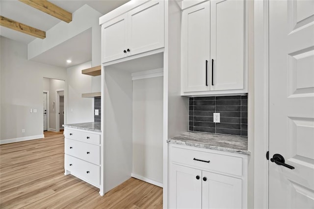 kitchen featuring white cabinets, light hardwood / wood-style floors, light stone counters, and beamed ceiling