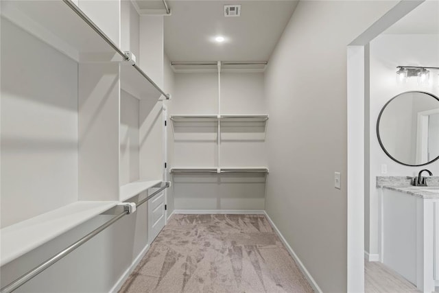 spacious closet featuring light colored carpet and sink