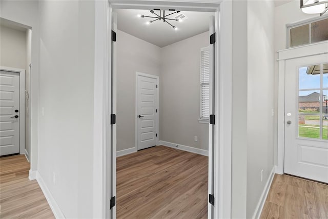 hallway with light hardwood / wood-style floors and a chandelier