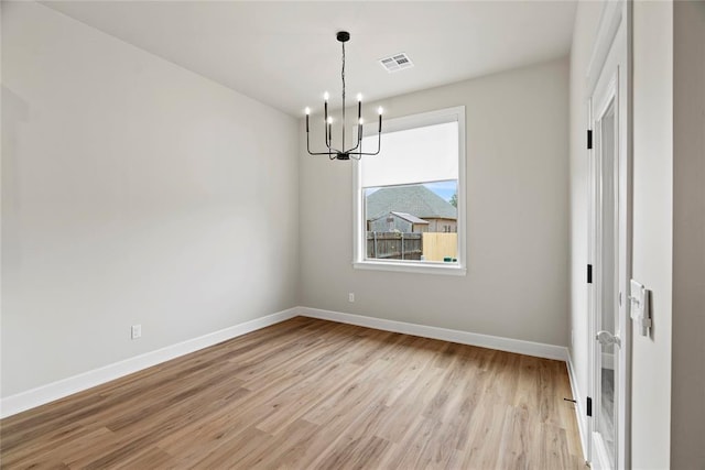 unfurnished dining area with light hardwood / wood-style floors and an inviting chandelier