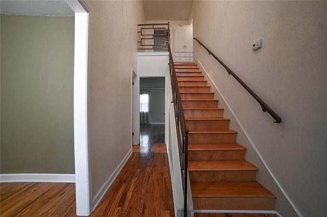 stairs with a high ceiling and wood-type flooring