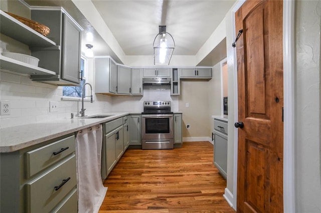 kitchen featuring sink, backsplash, stainless steel appliances, light stone countertops, and light wood-type flooring