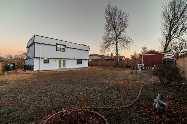 back house at dusk with french doors and central air condition unit