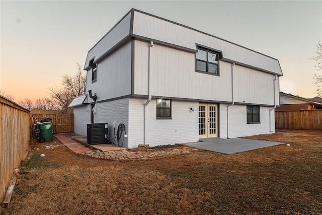 back house at dusk featuring french doors, a patio, and central air condition unit