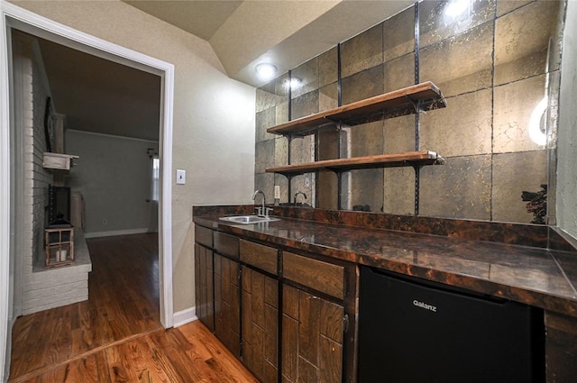 bar with dark hardwood / wood-style flooring, sink, and dark brown cabinetry