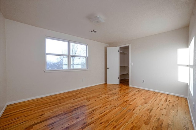 unfurnished bedroom featuring a spacious closet, light hardwood / wood-style floors, and a closet