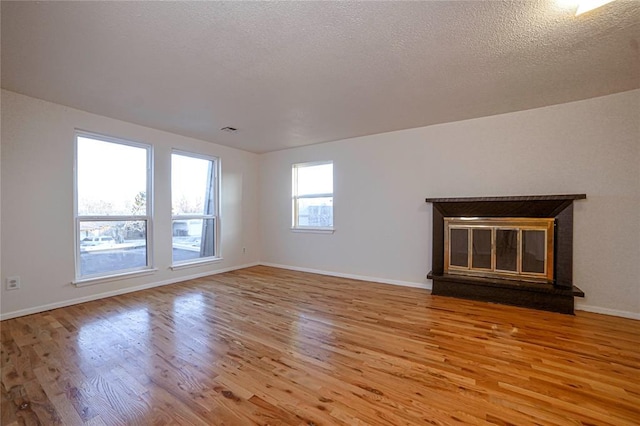 unfurnished living room with a textured ceiling and light hardwood / wood-style floors