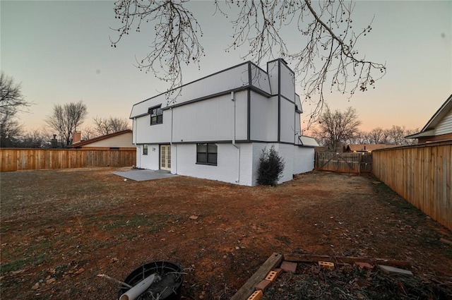 back house at dusk with a patio area