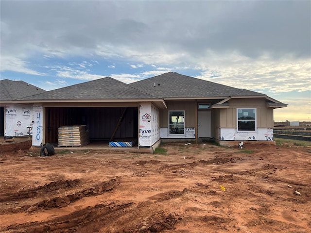 unfinished property with an attached garage and a shingled roof