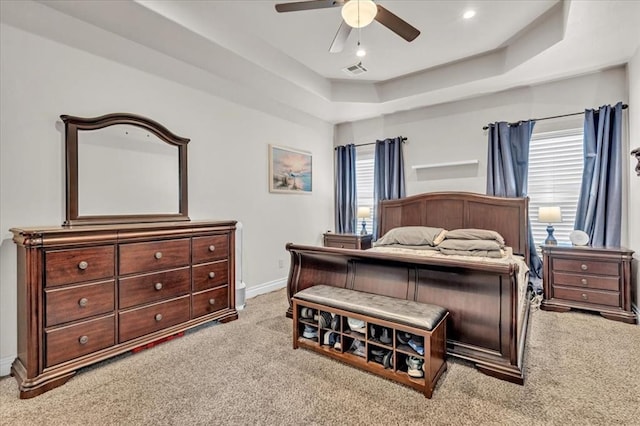 bedroom with ceiling fan, light carpet, and a tray ceiling