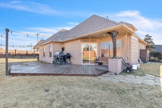 back of property featuring a yard, fence, a deck, and roof with shingles