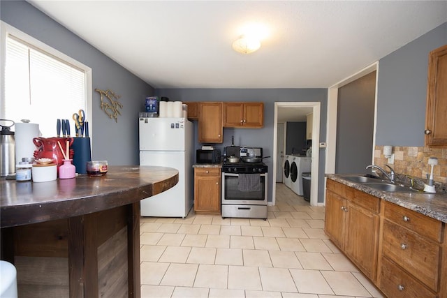 kitchen featuring white refrigerator, sink, decorative backsplash, separate washer and dryer, and stainless steel range