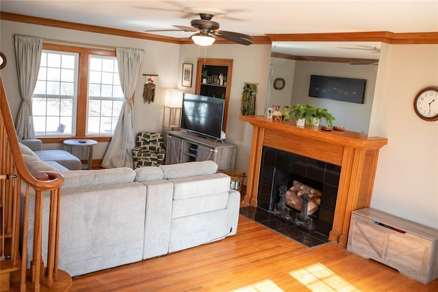 living room with a fireplace, crown molding, wood-type flooring, and ceiling fan