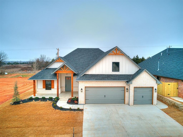 view of front facade with board and batten siding, brick siding, concrete driveway, and roof with shingles