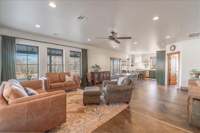 living room featuring ceiling fan and concrete floors