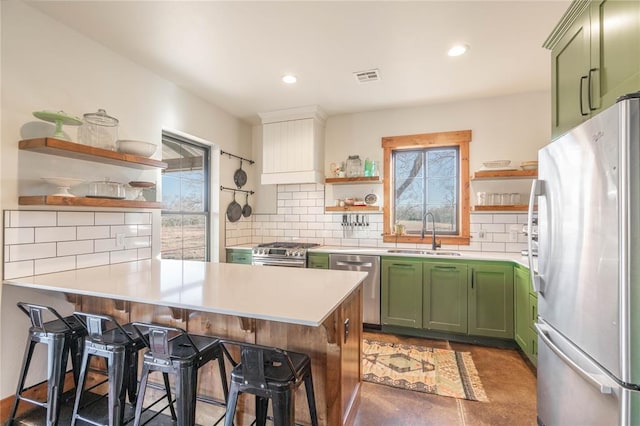 kitchen featuring kitchen peninsula, stainless steel appliances, green cabinets, and sink