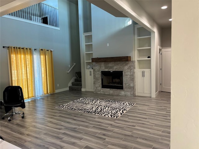 living room featuring built in features, hardwood / wood-style flooring, and a stone fireplace