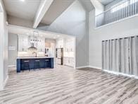 living room featuring radiator, light hardwood / wood-style flooring, a high ceiling, and beamed ceiling