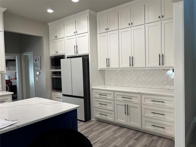 kitchen featuring oven, light hardwood / wood-style floors, decorative backsplash, fridge, and white cabinetry