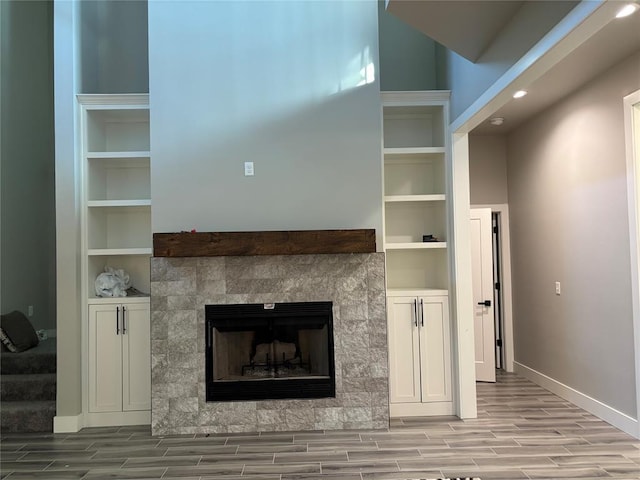 unfurnished living room with light hardwood / wood-style floors, built in shelves, and a tile fireplace