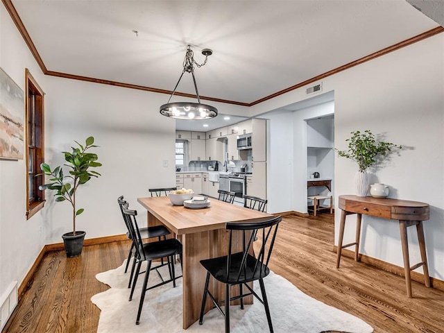 dining area featuring ornamental molding and light wood-type flooring