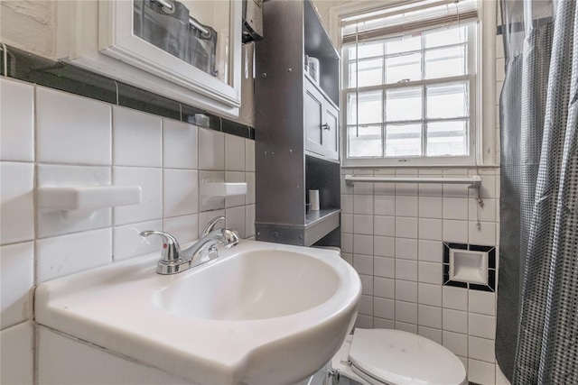 bathroom with a shower with shower curtain, toilet, tile walls, and sink