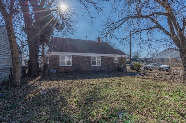 back of property featuring central AC unit and a yard