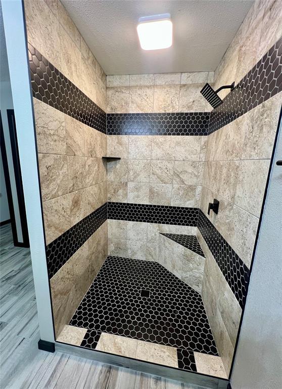 bathroom with a tile shower, hardwood / wood-style flooring, and a textured ceiling