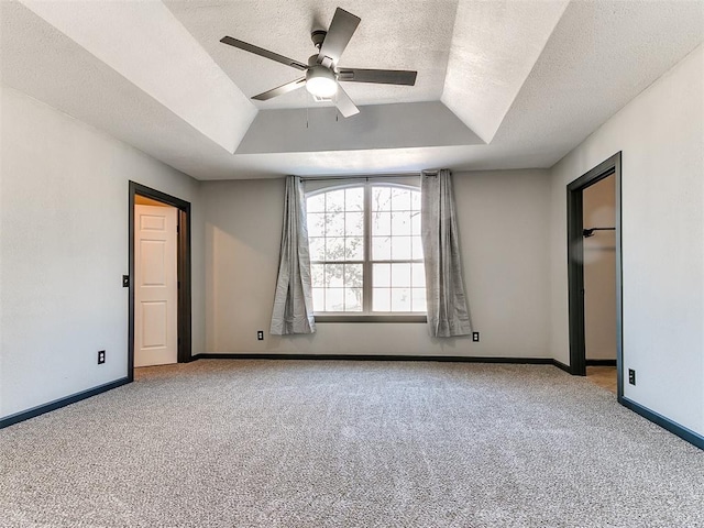 unfurnished bedroom featuring ceiling fan, a tray ceiling, light colored carpet, and a textured ceiling