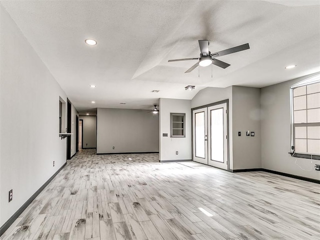 unfurnished living room with vaulted ceiling, ceiling fan, light hardwood / wood-style floors, a textured ceiling, and french doors