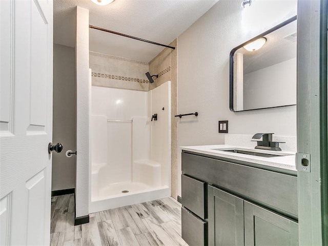 bathroom featuring wood-type flooring, vanity, a textured ceiling, and walk in shower