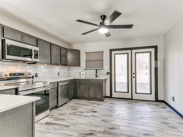 kitchen featuring appliances with stainless steel finishes, sink, decorative backsplash, dark brown cabinetry, and light hardwood / wood-style floors