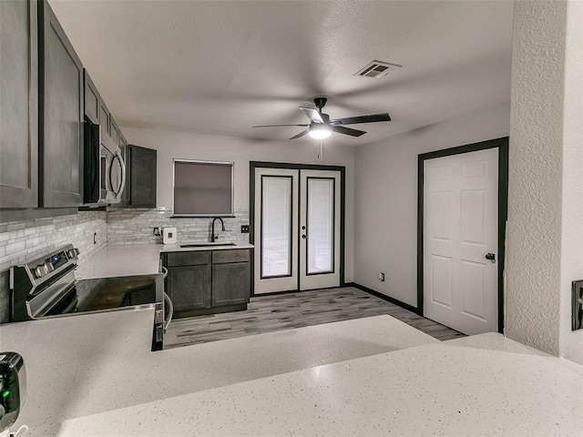 kitchen featuring sink, tasteful backsplash, light hardwood / wood-style flooring, appliances with stainless steel finishes, and ceiling fan