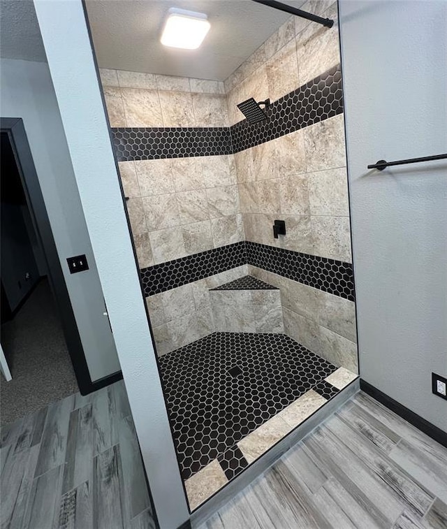 bathroom with a textured ceiling and a tile shower