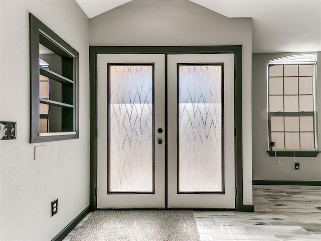 doorway to outside with french doors, vaulted ceiling, and light wood-type flooring