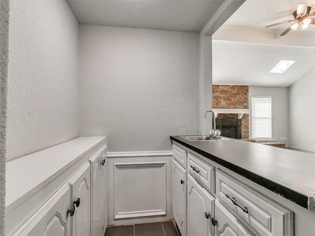 kitchen featuring white cabinets, a skylight, tile patterned floors, and sink