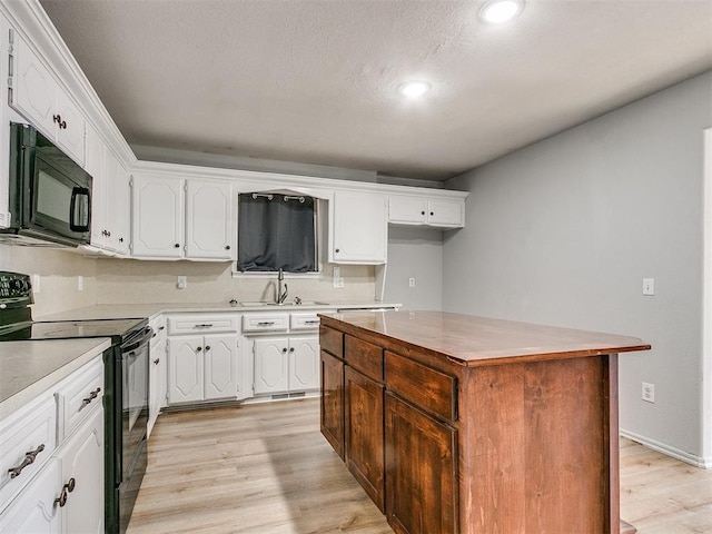 kitchen featuring black appliances, white cabinetry, sink, and a kitchen island