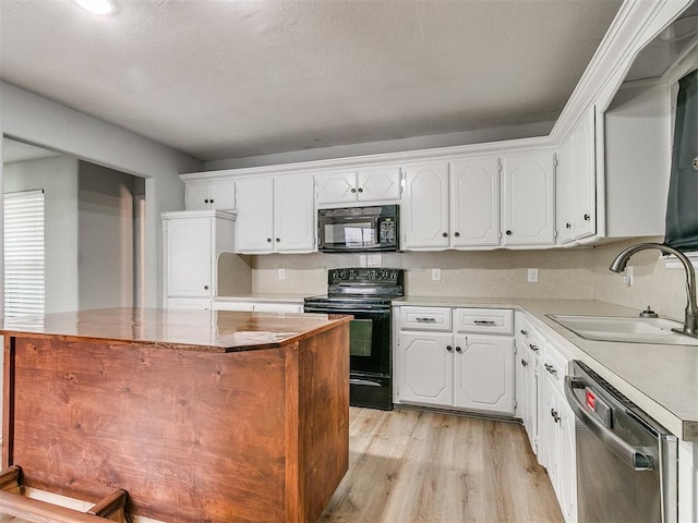 kitchen with sink, white cabinetry, black appliances, and a center island