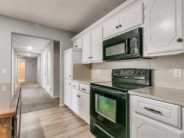 kitchen featuring backsplash, white cabinets, black appliances, and light hardwood / wood-style floors