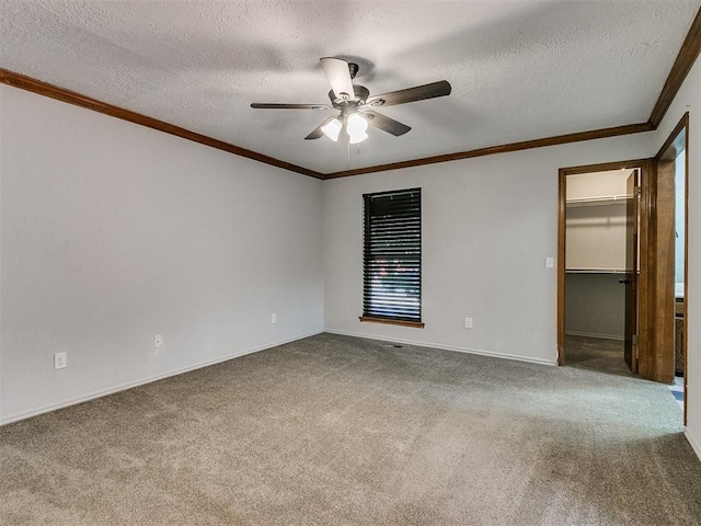 empty room with carpet floors, a textured ceiling, and crown molding