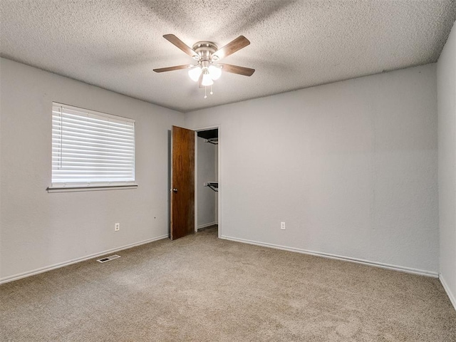 empty room featuring a textured ceiling, ceiling fan, and light colored carpet