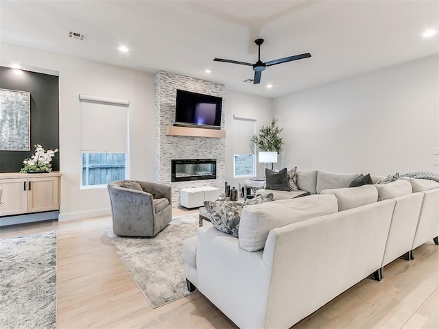 living room with a fireplace, ceiling fan, and light hardwood / wood-style flooring