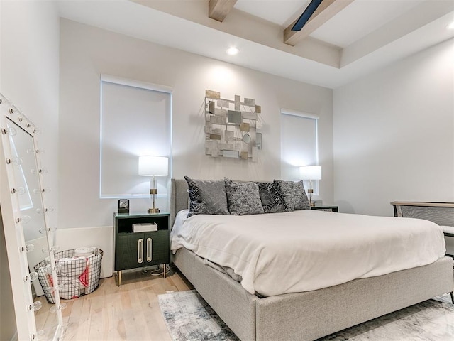 bedroom with beamed ceiling, ceiling fan, and wood-type flooring