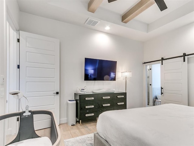 bedroom with ceiling fan, beam ceiling, a barn door, and light wood-type flooring