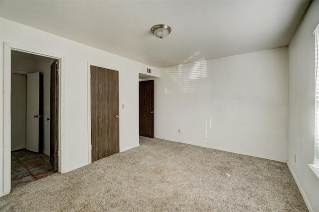 unfurnished bedroom with light carpet, a textured ceiling, and a closet