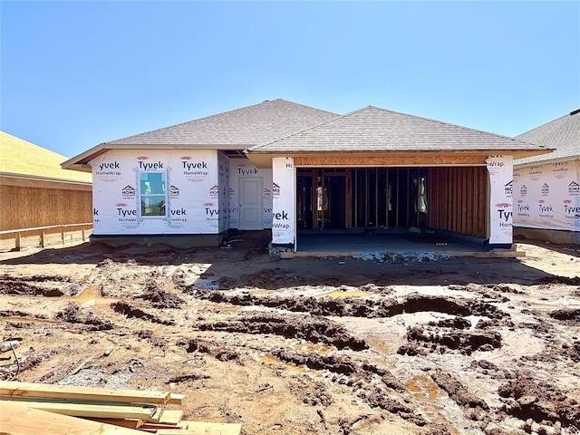 unfinished property with an attached garage and roof with shingles