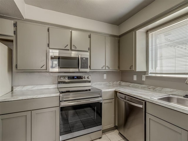 kitchen with gray cabinets, light tile patterned flooring, sink, and appliances with stainless steel finishes