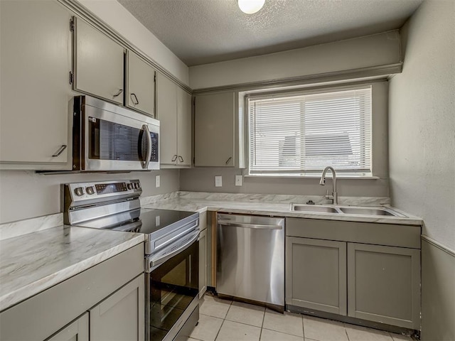 kitchen with gray cabinetry, sink, stainless steel appliances, a textured ceiling, and light tile patterned floors