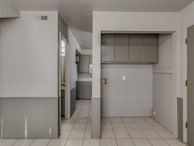 kitchen with gray cabinets, light tile patterned flooring, and a textured ceiling