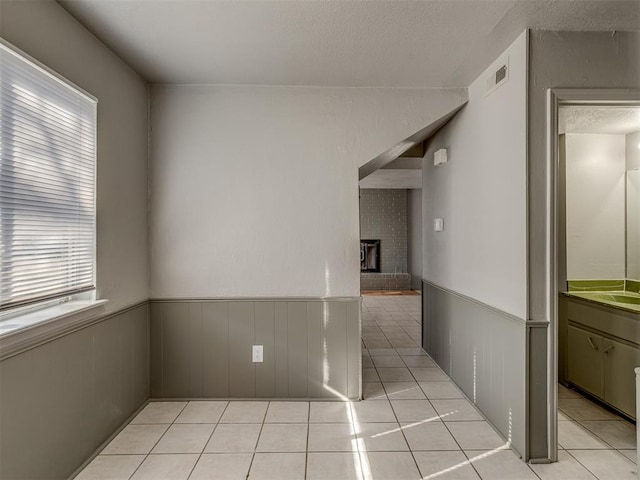 unfurnished room with a wealth of natural light, a fireplace, and light tile patterned flooring